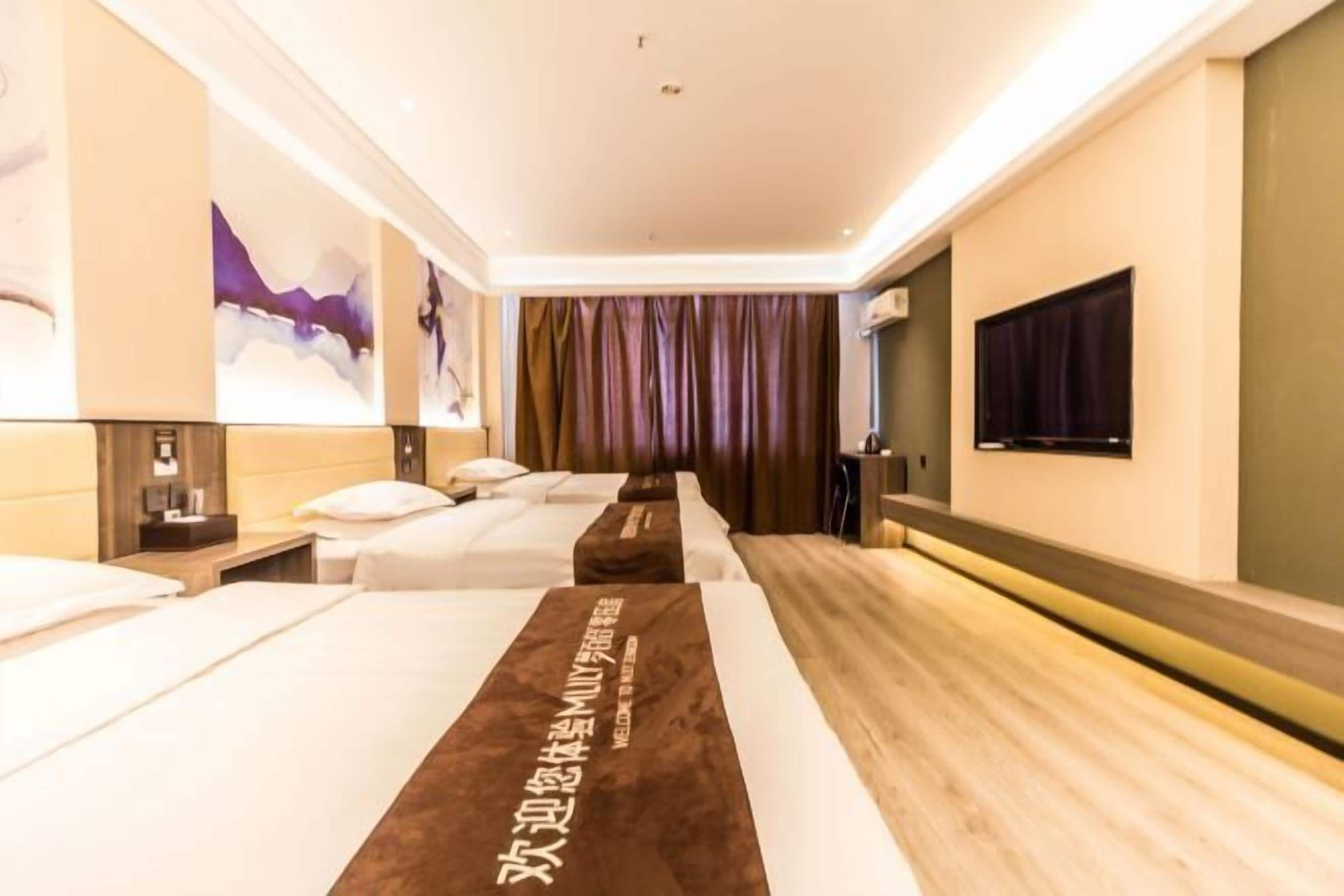 A hotel room with two beds, a wooden bench, a TV, and a wall-mounted artwork.