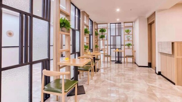 A modern interior with wooden tables and chairs, potted plants, and a marble floor. - Yanji Moka Boutique Hotel (Yanji)