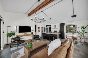 A modern living space with a central seating area, a kitchen, and a dining area.
