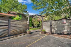A gated parking area with a metal gate and a wooden pergola structure.