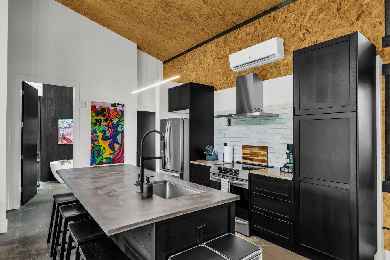 A modern kitchen with a central island, stainless steel appliances, and a wooden ceiling.