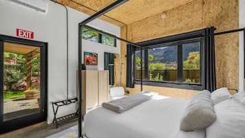 Ein modernes Schlafzimmer mit einem großen Bett, einem Fluchtwegschild und Blick auf eine gebirgige Landschaft.