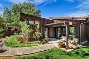 Ein modernes Haus mit Terrasse, Sitzgelegenheiten im Freien und einem gepflegten Garten.