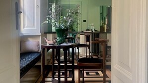 A narrow hallway with a wooden bench, a dining table with chairs, a potted plant, and a geometric patterned floor. - Milan Royal Suites - Brera (Milan)