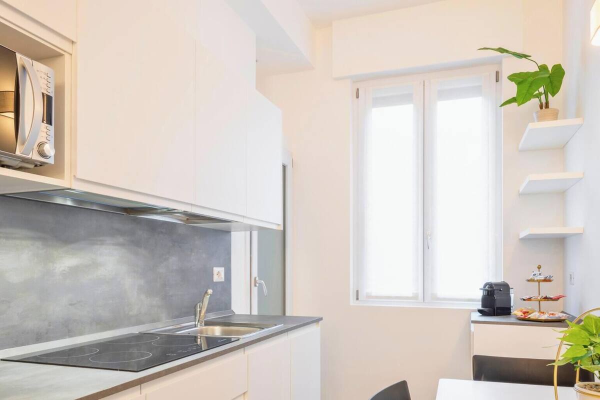 A modern kitchen with white cabinetry, a built-in microwave, a gas stove, and a window providing natural light.