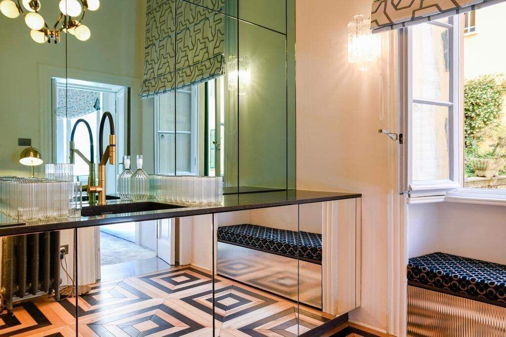 A modern bathroom with a large mirror, a black countertop, and a patterned floor.