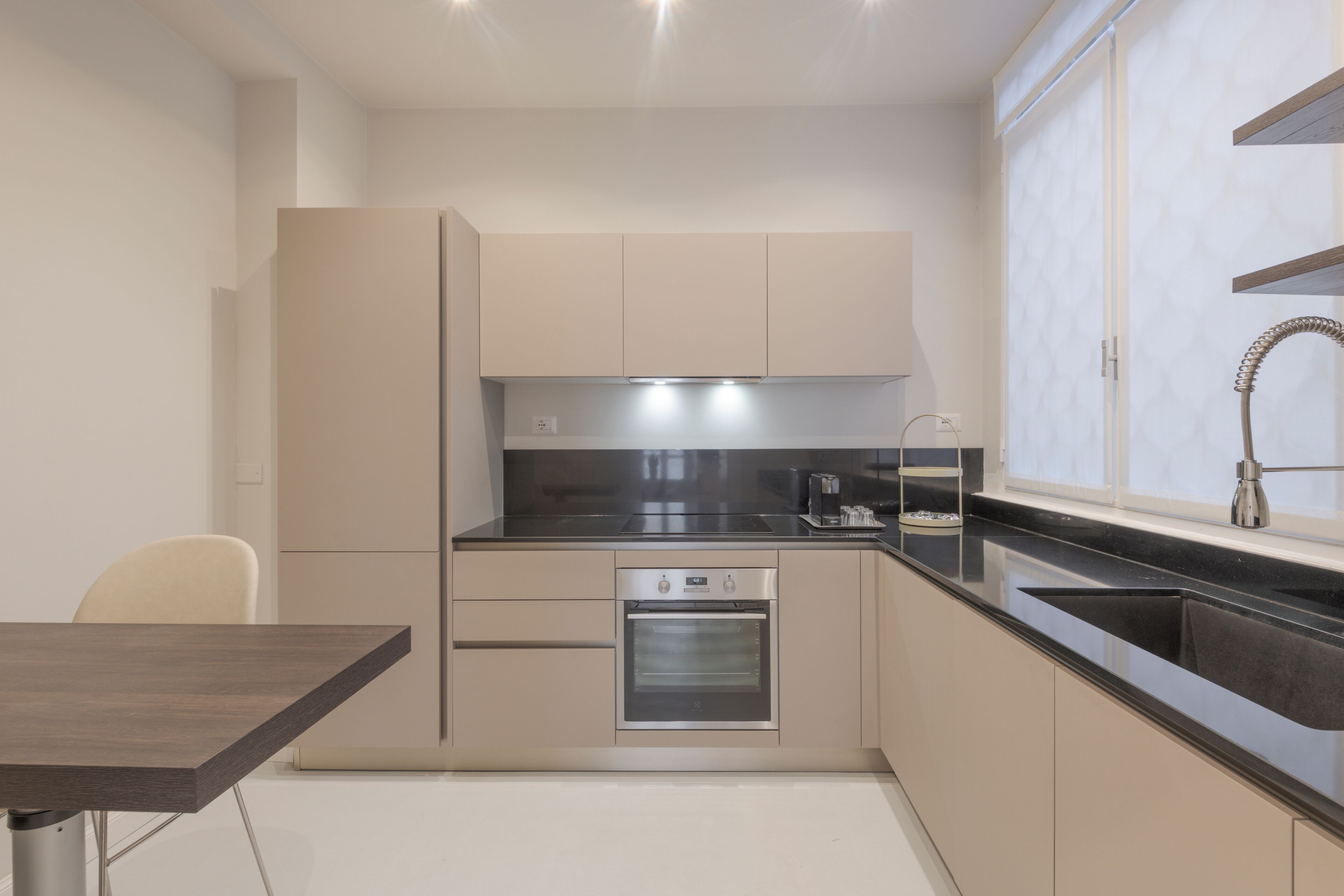 A modern kitchen with a built-in oven, a sink, and a window with a view.