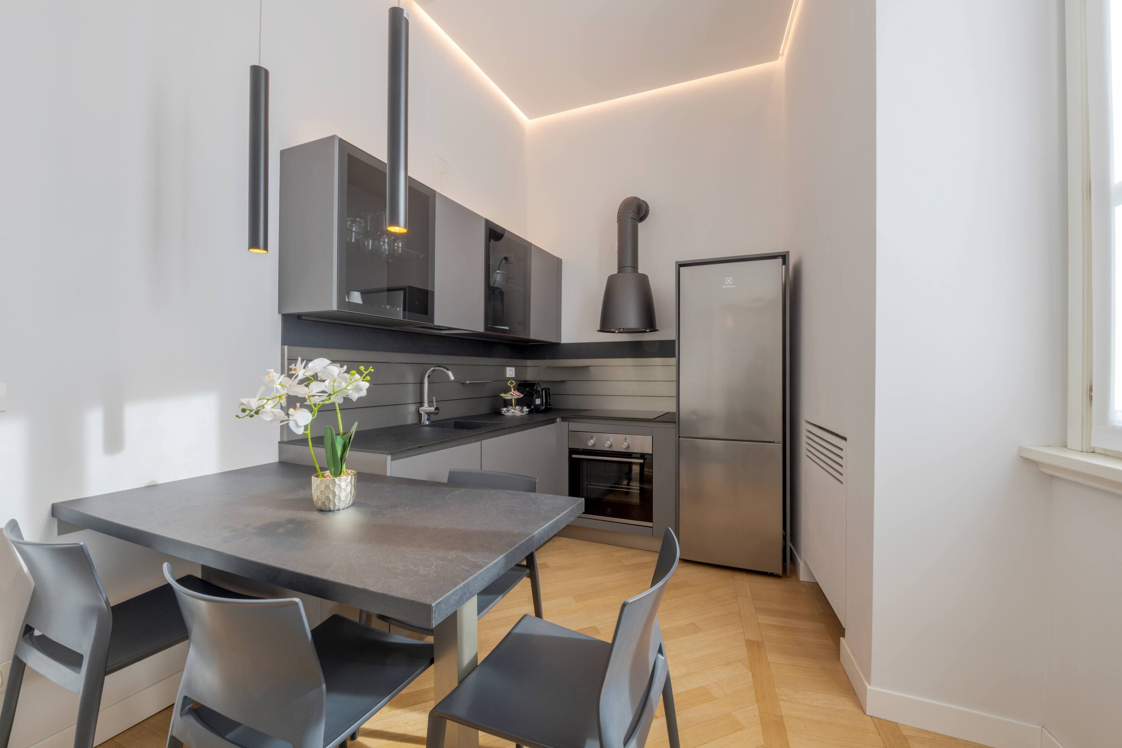 Une cuisine moderne avec une table à manger, des chaises et un vase de fleurs.