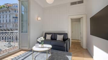Uma sala de estar moderna com um sofá, uma mesa de centro e vista para o horizonte urbano através de grandes janelas.