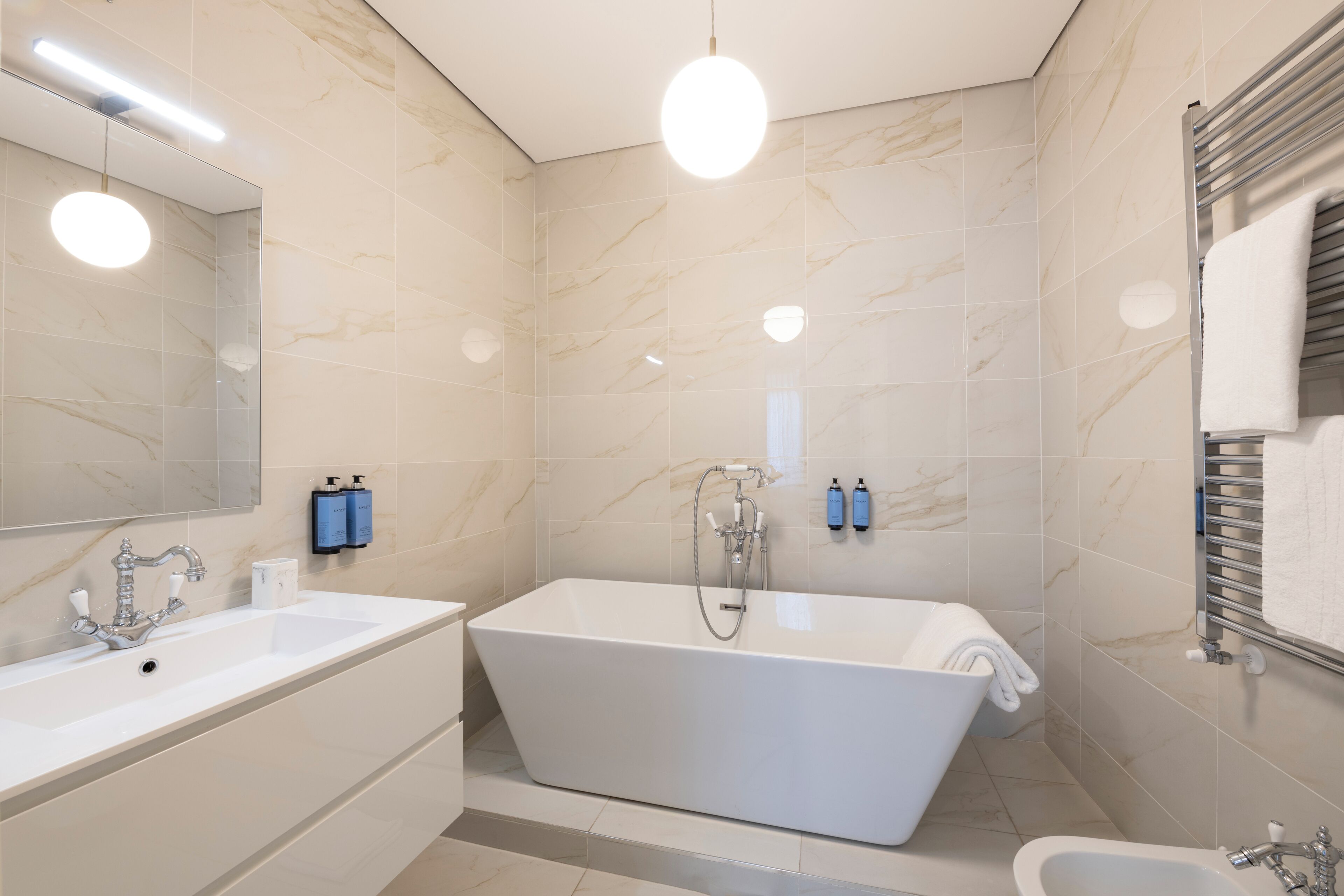Een moderne badkamer met een vrijstaand bad, een dubbele wastafel en een grote spiegel.
