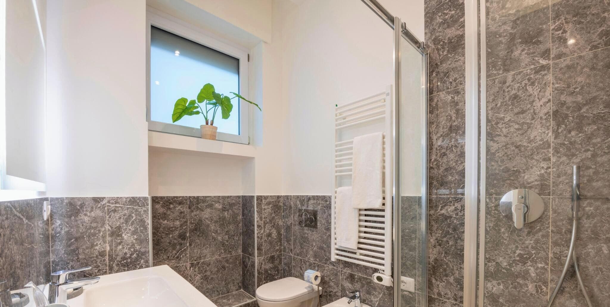 Een moderne badkamer met douche, toilet en wastafel.