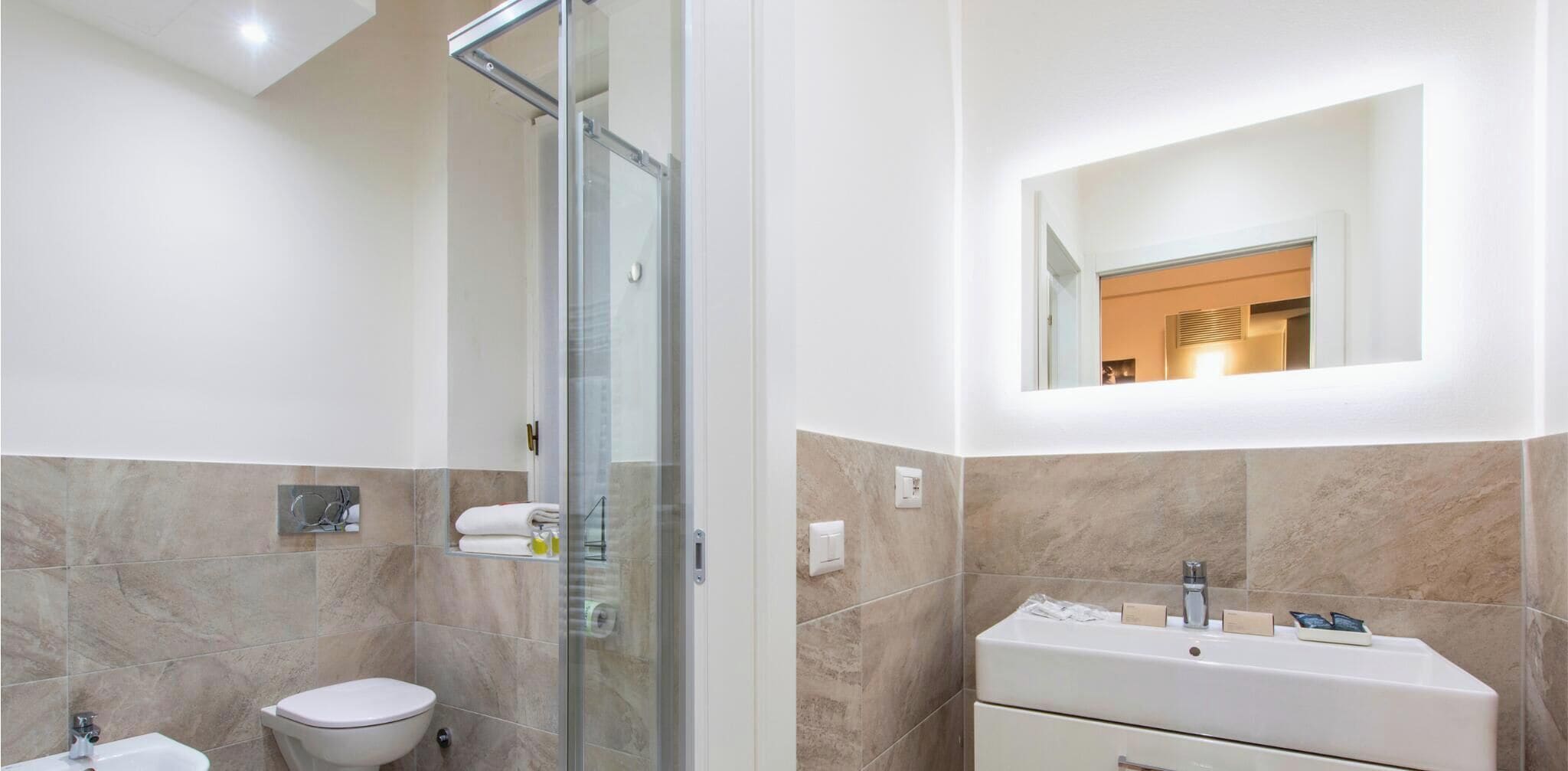 Un baño moderno con cabina de ducha de vidrio, un inodoro, un lavabo con espejo y tocador.