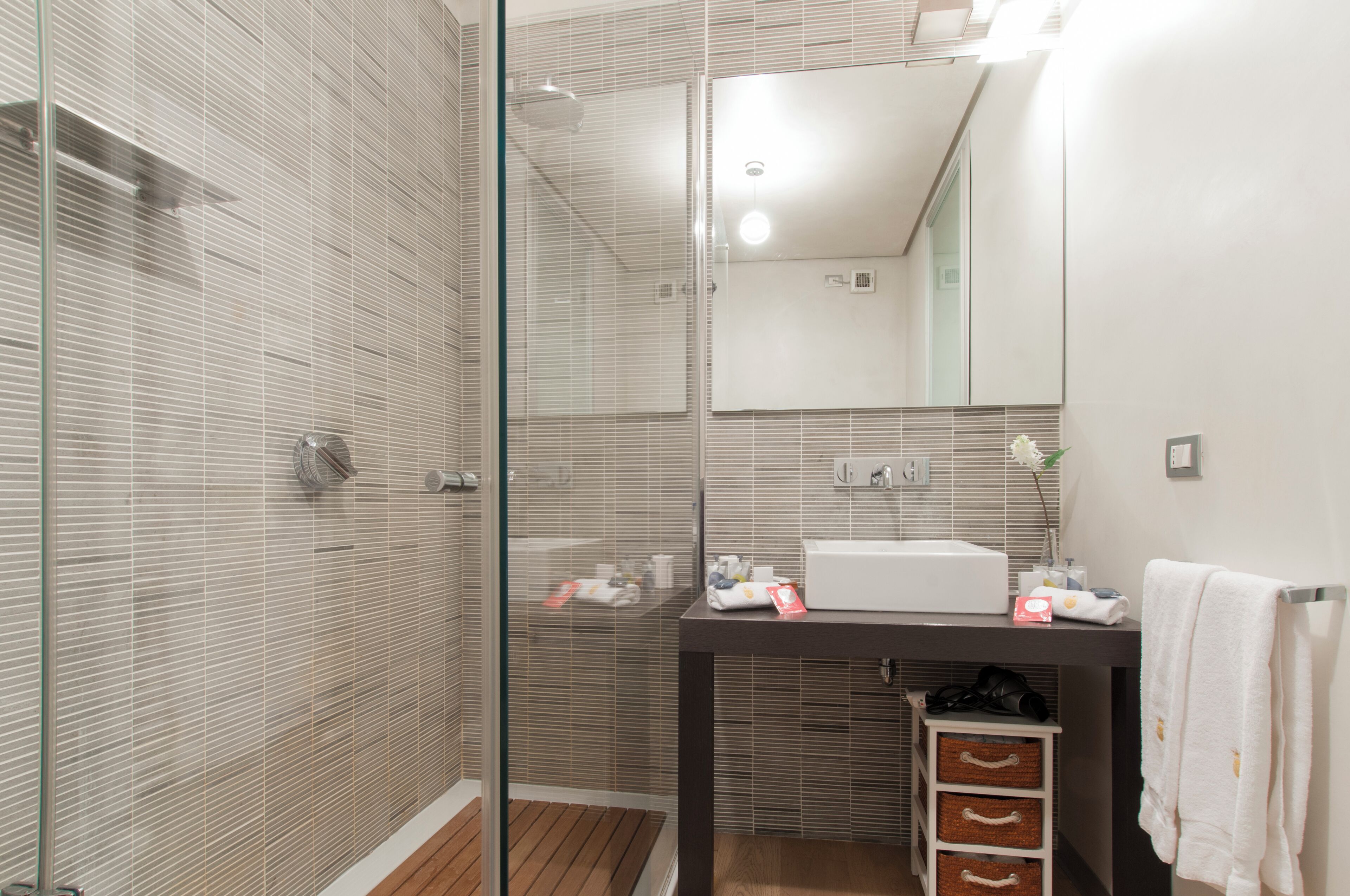 A modern bathroom with a glass shower enclosure, a white sink, and a mirror above the sink.