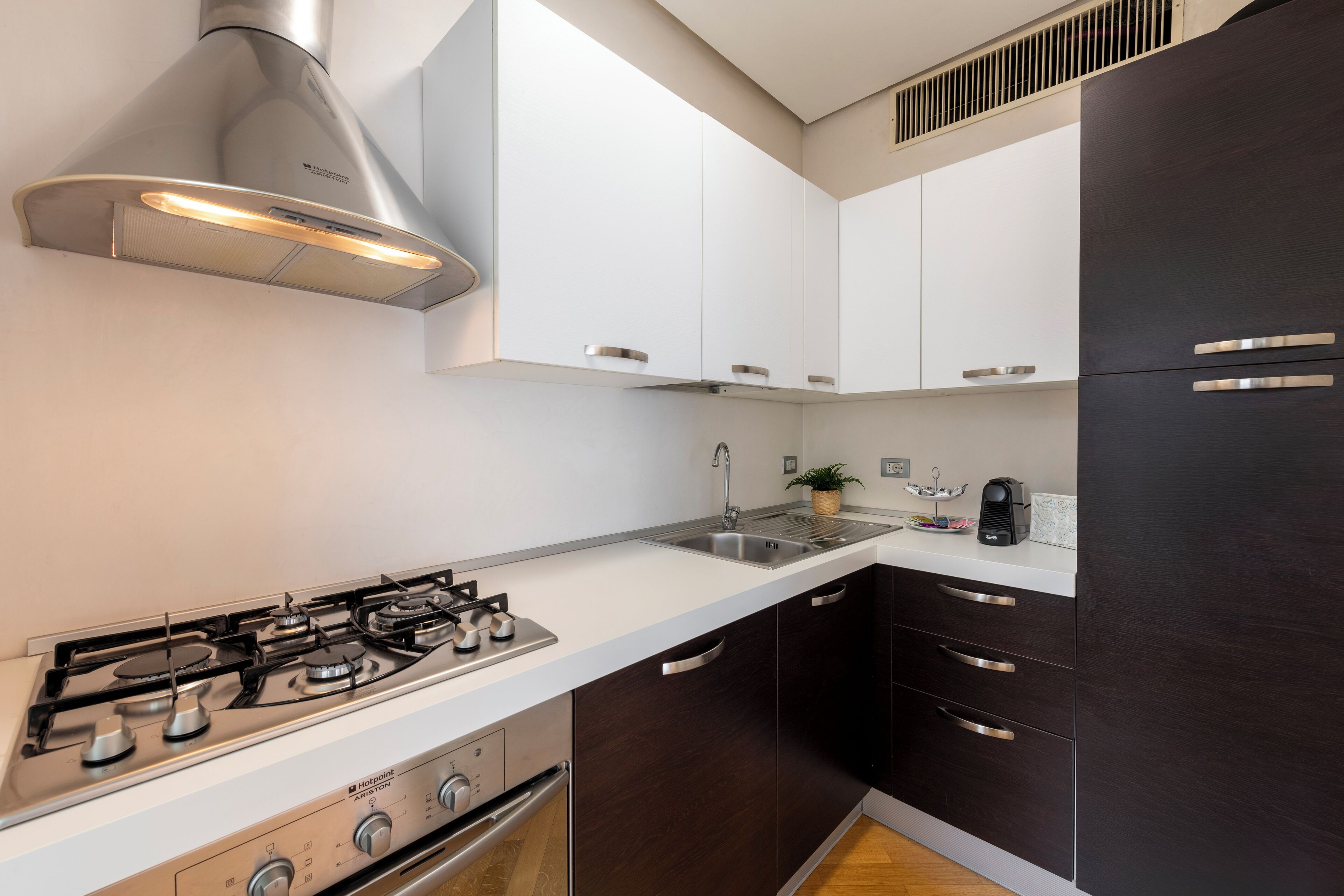 A modern kitchen with a gas stove, stainless steel cabinets, and a black refrigerator.