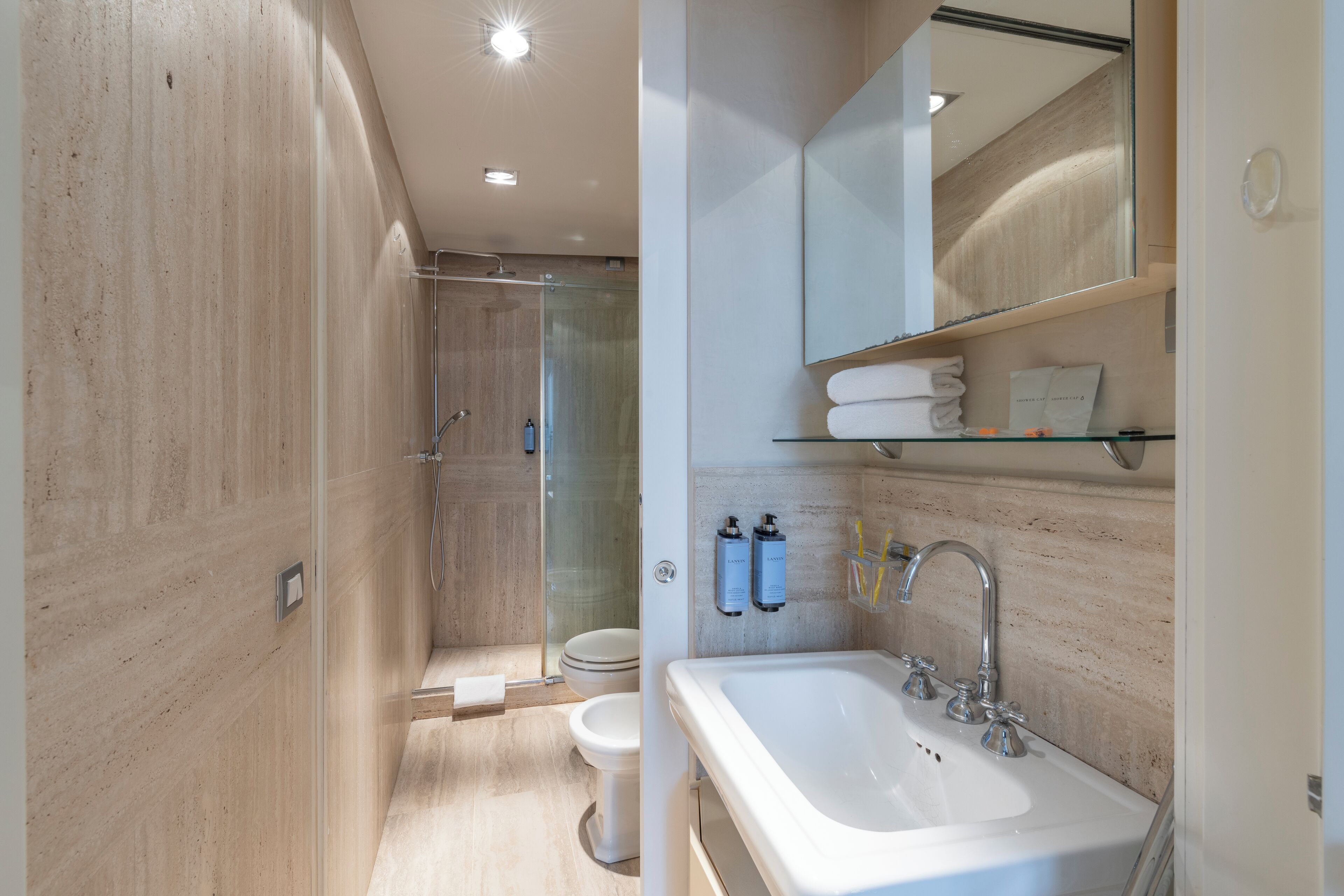 A modern bathroom with a glass-enclosed shower, a white sink, and a mirror above the sink.