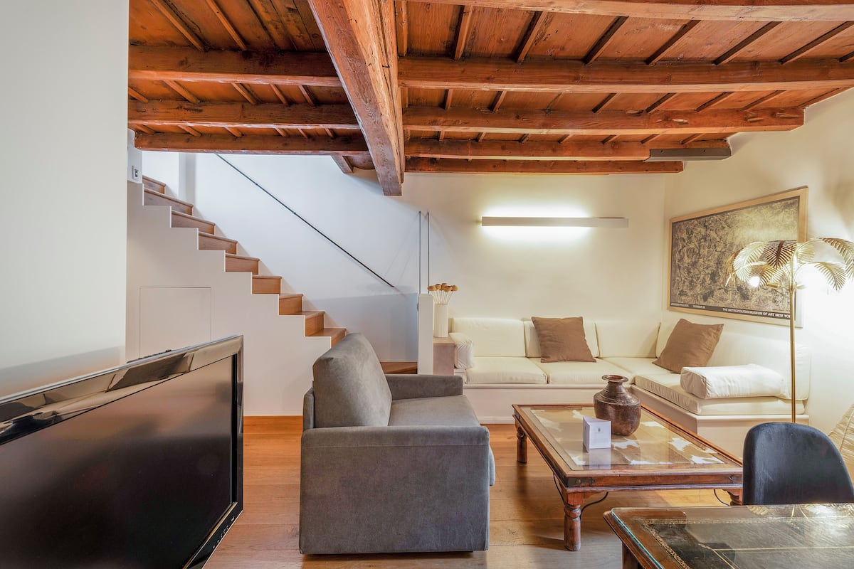 A living room with a sofa, a coffee table, a TV, and a staircase.