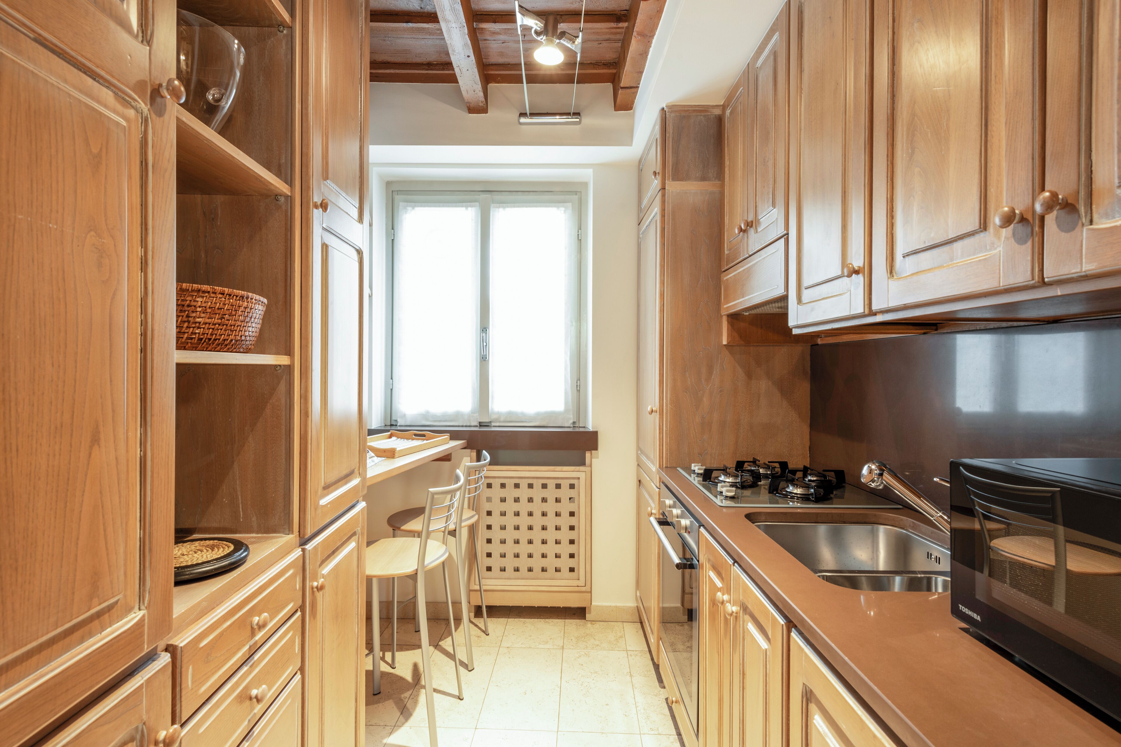 A kitchen with wooden cabinets, a stove, and a sink.
