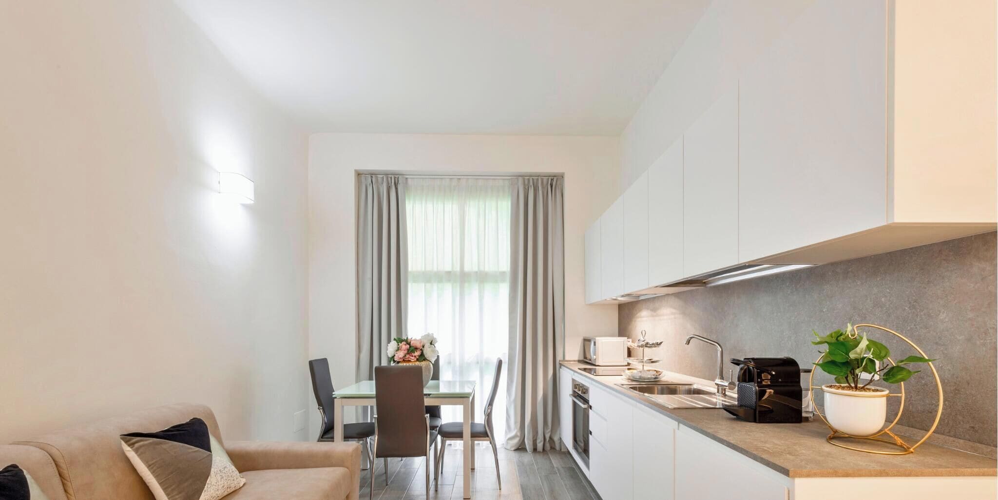 Una cocina moderna con comedor, que incluye una mesa con sillas, un sofá y una planta en maceta.