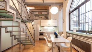 A modern kitchen with a staircase, white chairs, and a dining table. - Milan Royal Suites - Brera (Milan)