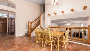 Ein Essbereich mit Holztisch und -stühlen, einer Treppe und einem Deckenventilator.