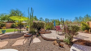 Eine Terrasse mit Gartenmöbeln, einer Feuerstelle und verschiedenen Pflanzen.