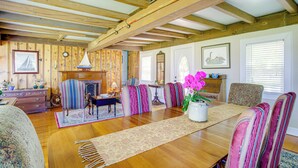 Un comedor de madera con una mesa larga, sillas a rayas y un jarrón con flores.