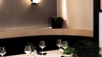 A dining area with a table set for two, a pendant light, and a wall-mounted light fixture.