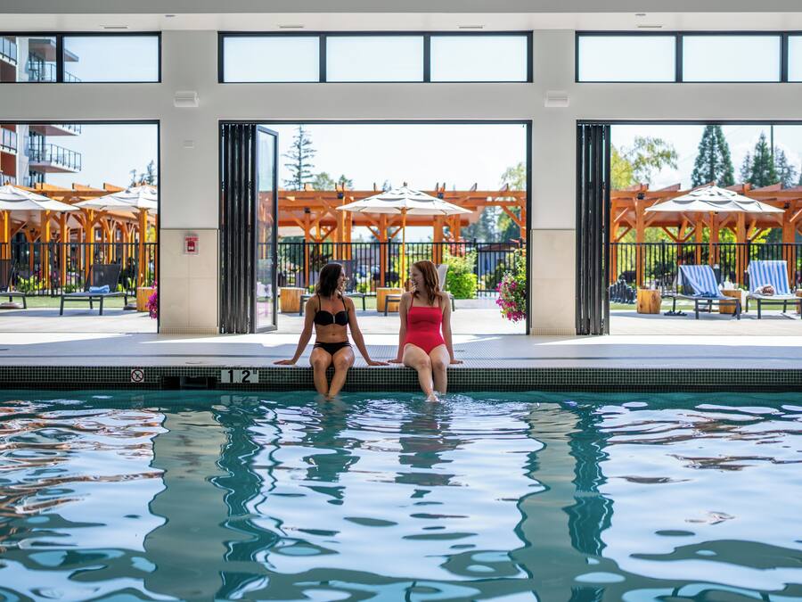A swimming pool with two women sitting at the edge.