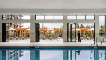 Una piscina techada, sombrillas, sillones reclinables de piscina