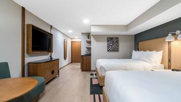 A modern hotel room with a wooden desk, a flat-screen TV, a bed with white linens, and a zebra-patterned artwork on the wall.