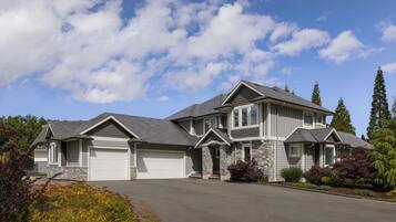 A two-story house with a garage, stone exterior, and landscaped garden.