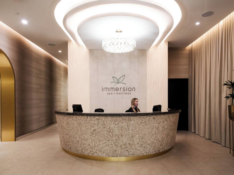 A reception desk with a logo, a chandelier, and a plant.