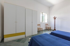 Une chambre avec deux lits simples, une armoire et une fenêtre.