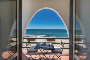 Un balcon avec une table et des chaises donnant sur l’océan.