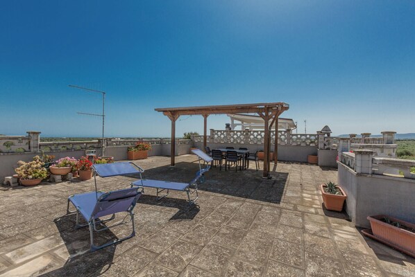 Terraza en la azotea con pérgola, zona de estar y plantas en macetas.