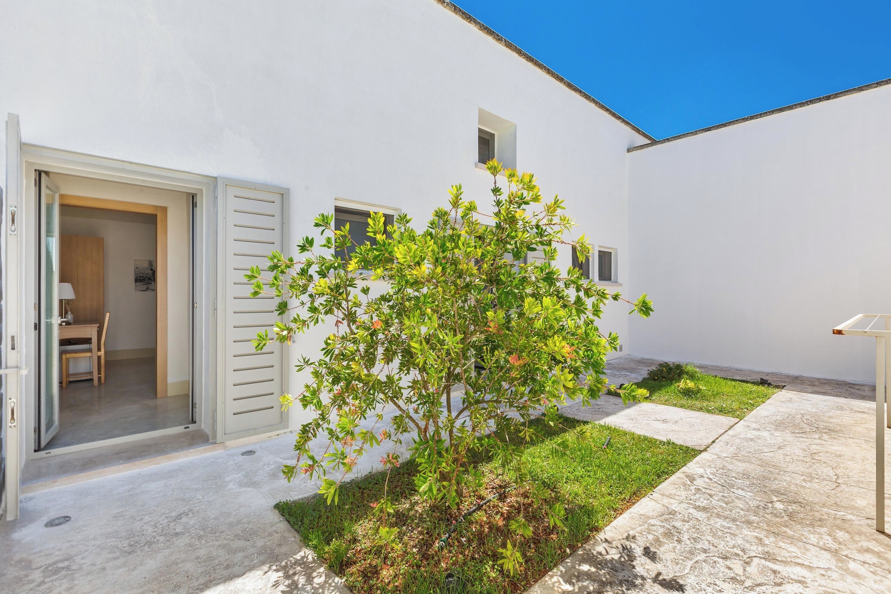 A white building with a small garden, a door, and a window.