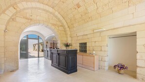 A spacious interior with a central black bar, stone walls, and a view through an archway.