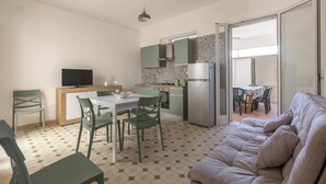 Un espacio habitable compacto con kitchenette, comedor y sofá.