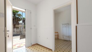 Una habitación con suelo de baldosas, paredes blancas y una puerta que da al exterior.