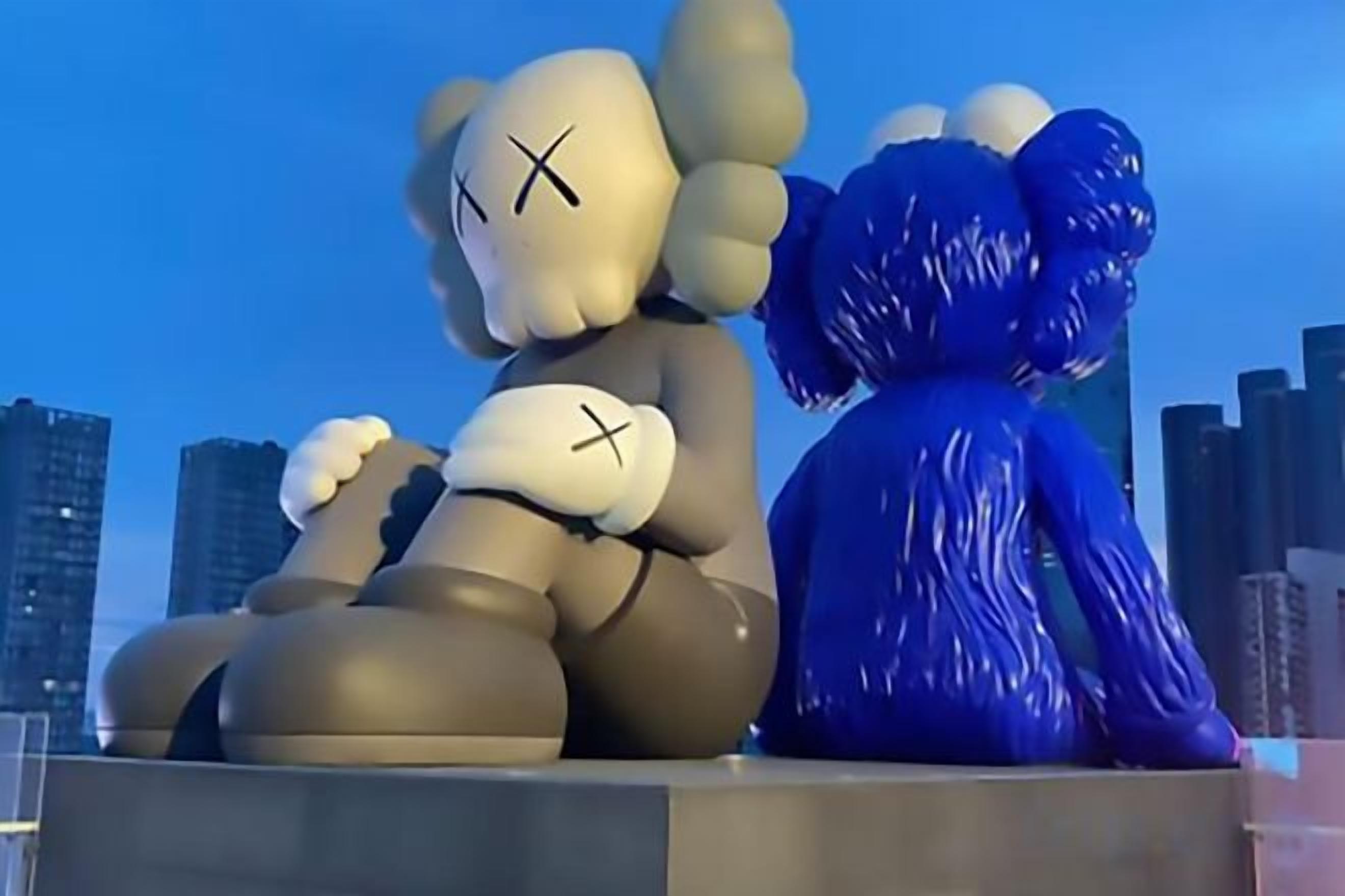 A sculpture of two figures, one with a cross on its chest and the other with a cross on its arm, set against a city skyline.