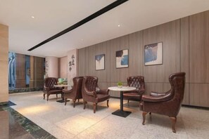 A lobby with leather armchairs, a round table, and artwork on the walls. - ChangSha Sanhe Hotel (Changsha)