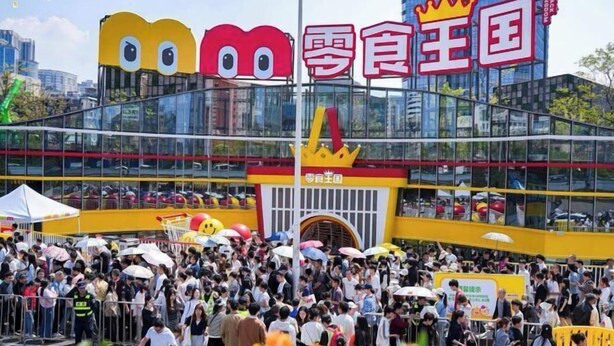 A crowded outdoor area with a large building featuring a distinctive yellow and red design. - ChangSha Sanhe Hotel (Changsha)