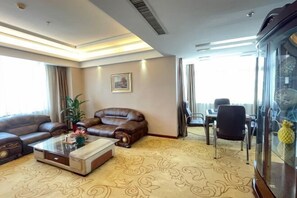 A hotel room with a sofa, a coffee table, a dining table with chairs, a large window, and a decorative glass cabinet. - ChangSha Sanhe Hotel (Changsha)