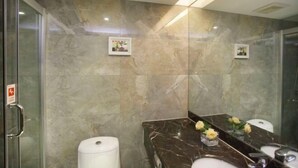 A modern bathroom with marble walls, a glass shower enclosure, and a vanity with a mirror. - ChangSha Sanhe Hotel (Changsha)