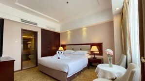 A hotel room with a large bed, bedside tables with lamps, a small round table with a vase, and a door leading to a bathroom. - ChangSha Sanhe Hotel (Changsha)