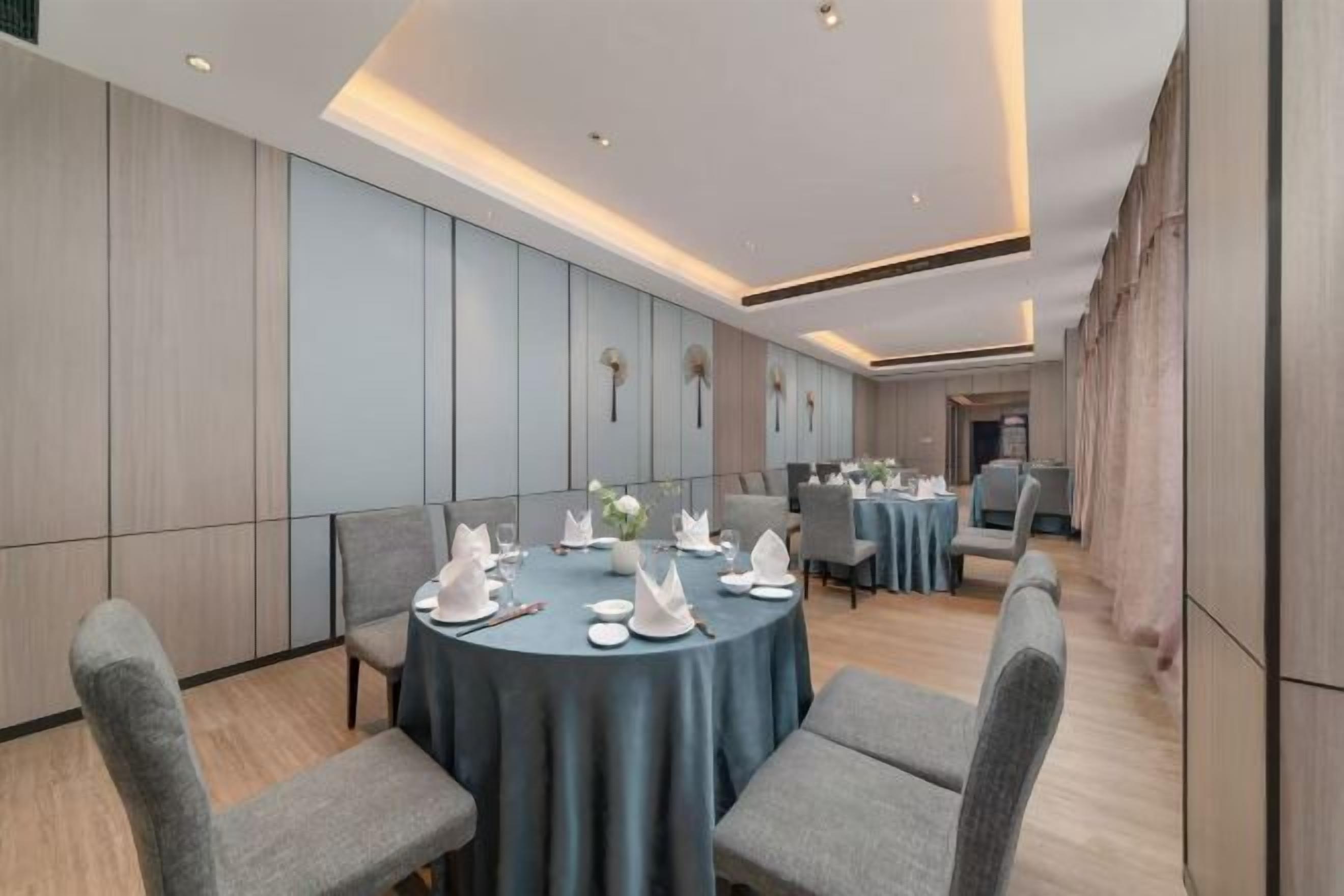 Un salón de conferencias con mesas redondas, sillas grises y un diseño interior moderno.