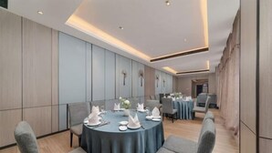 Una sala conferenze con tavoli rotondi, sedie grigie e un design d'interni moderno.