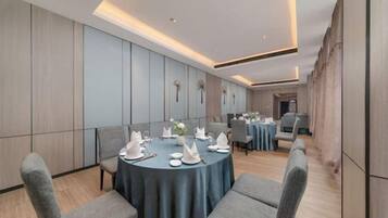 Un salón de conferencias con mesas redondas, sillas grises y un diseño interior moderno.