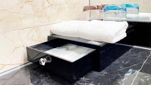 A bathroom with a marble wall, a black sink, and a white towel on a shelf. - ChangSha Sanhe Hotel (Changsha)