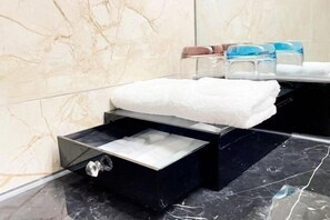 A bathroom with a marble wall, a black sink, and a white towel on a shelf. - ChangSha Sanhe Hotel (Changsha)